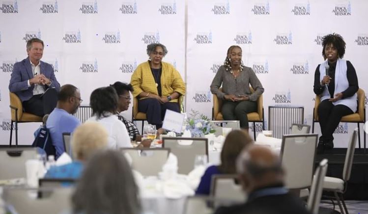 This image depicts a group of professionals seated on chairs at a conference.